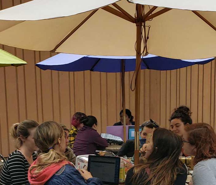 People enjoying lunch under a umbrella
