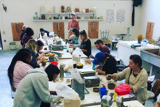People working on pottery projects in a ceramics studio