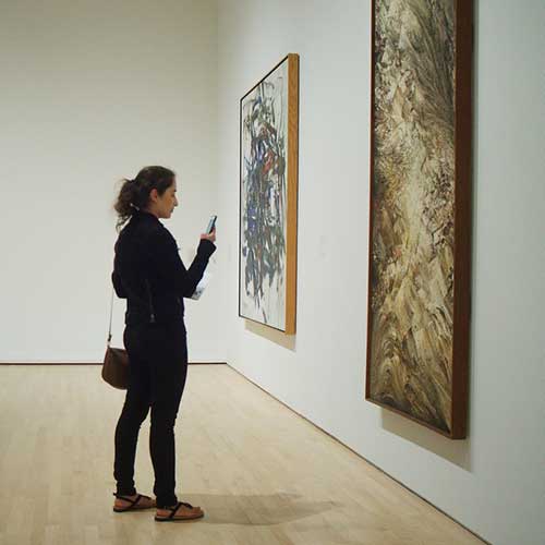 Woman looking at art on a wall.