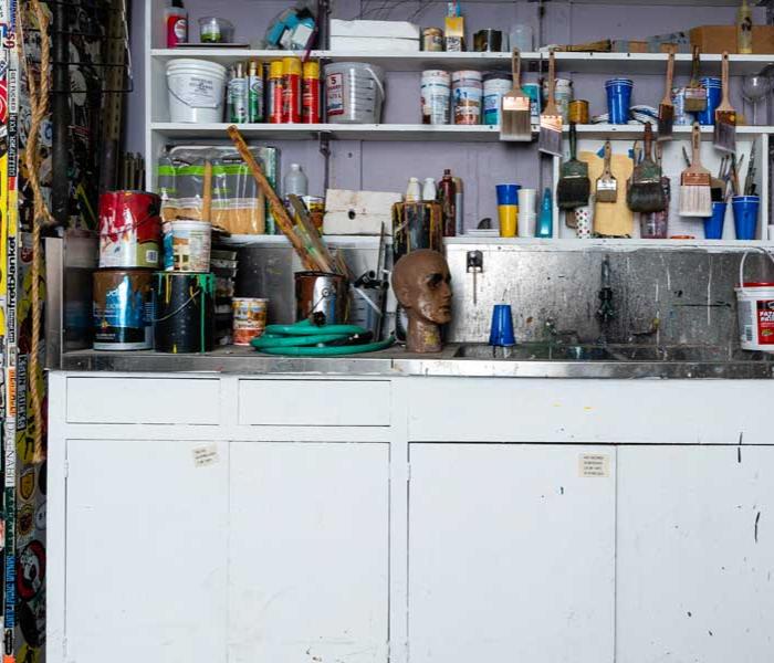 Paintbrushes and paint cans on a shelf.