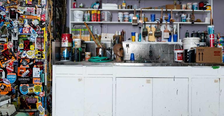 Paintbrushes and paint cans on a shelf.
